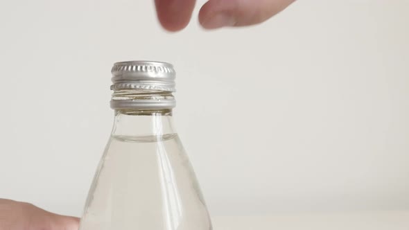 Unscrewing metal cap from glass bottle with fingers 4K footage