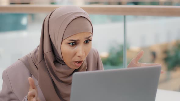 Young Worried Stressed Arab Businesswoman in Hijab Looking at Laptop Screen Feeling Shocked Annoyed alt