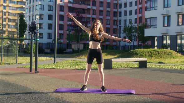 Young Woman in Black Sportswear is Stretching on Sports Ground and Bending to Left and Right alt
