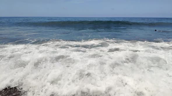 Horizon view from a volcanic beach in Canary Islands. Beach sand is black. Waves clashing by the sho alt