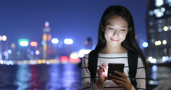 Young Woman Looking at Mobile Phone in City at Night