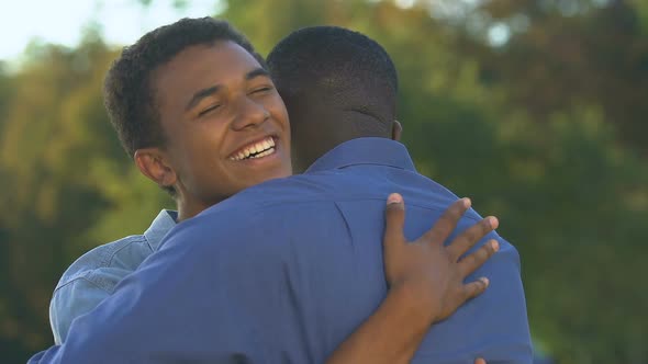Smiling Afro-American Man Hugging Teenage Son, Feeling Happy and Proud, Trust alt