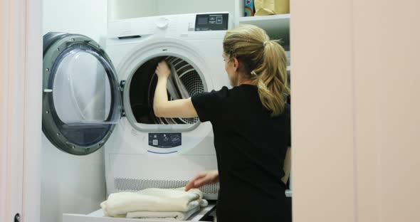 The Woman Takes Towels Out of the Washing Machine alt