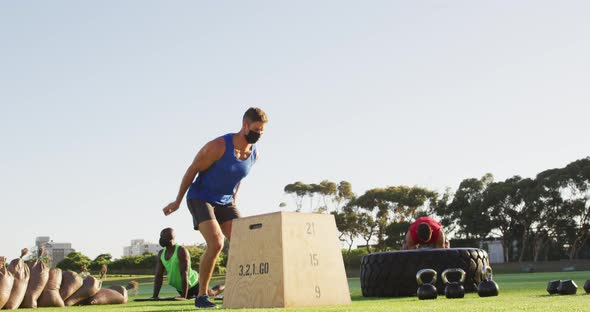 Diverse group of fit men wearing masks cross training outdoors alt