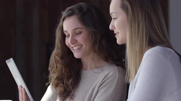 Two young women working together with digital tablet