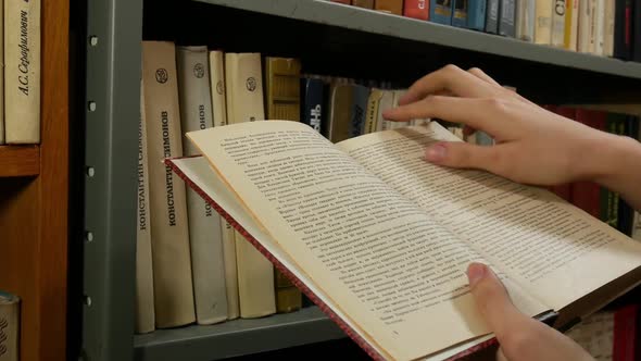 Girl Turning Book Pages In Front Of The Shelf