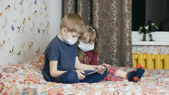 Masked Boy and Girl Using a Tablet alt