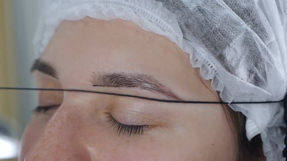 Cosmetologist Preparing Woman for Eyebrow Permanent Makeup Procedure Closeup