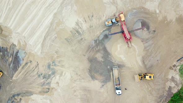 Excavator loader in sand quarry. View from above. Aerial view dumper trucks with cargo sand ridesing alt