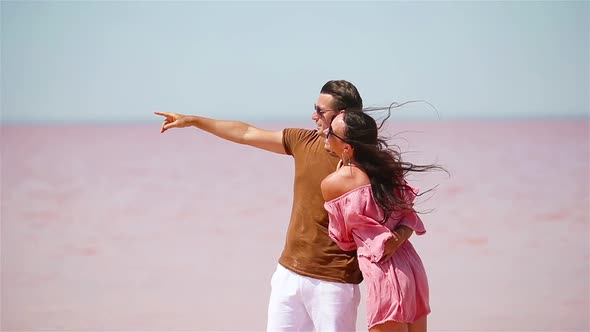 Family Walk on a Pink Salt Lake on a Sunny Summer Day.