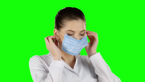 Young Doctor Putting on Health Mask, Green Screen, Closeup alt
