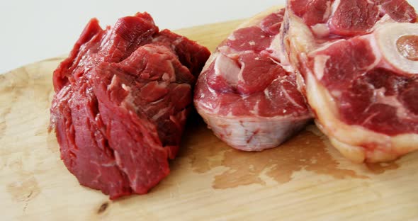 Three pieces of raw meat on chopping board alt