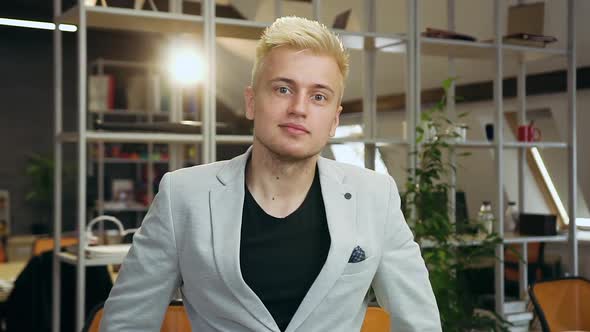 Young Man Standing in Contemporary Office Room and Posing on Camera alt