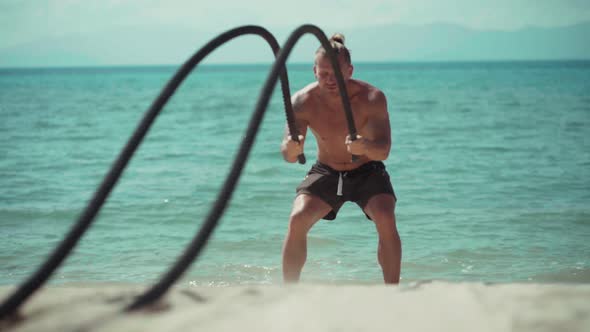 Man Training with Battle Rope on the Beach alt