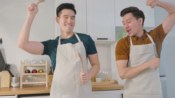 Asian happy handsome man gay couple sing and dance together in kitchen. alt