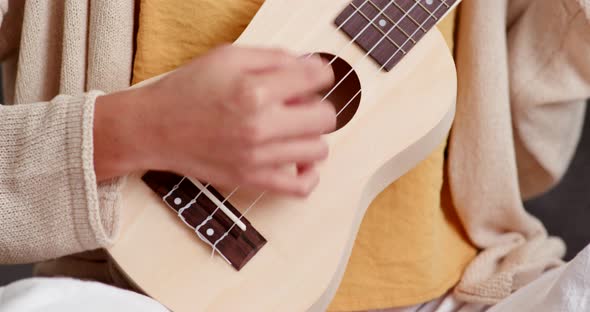Girl playing ukulele at home alt