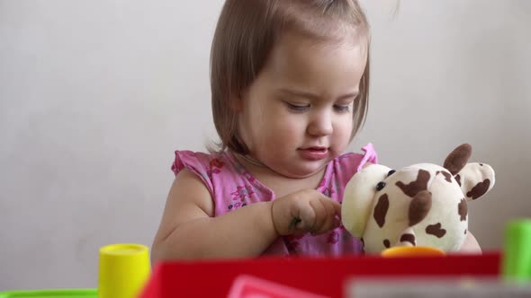 Small Toddler Girl Making Funny Expressive Grimace Face Playing with Soft Toy Bear at Home