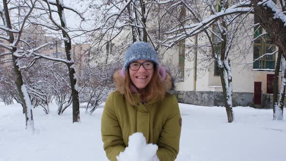 Young Woman Throws Fluffy Snow and Laughing