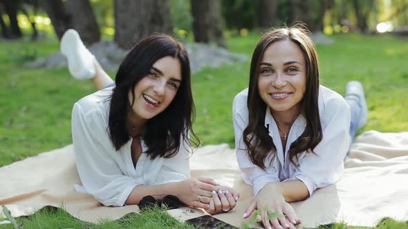 Two Cute Positive Girls Looking at Camera and Smiling, Singing and Moving, Talking To Camera, Lying alt