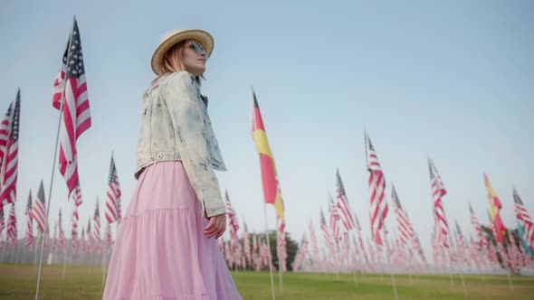 Stylish Woman Walking in Memorial Park with Many American and German Flagpoles alt