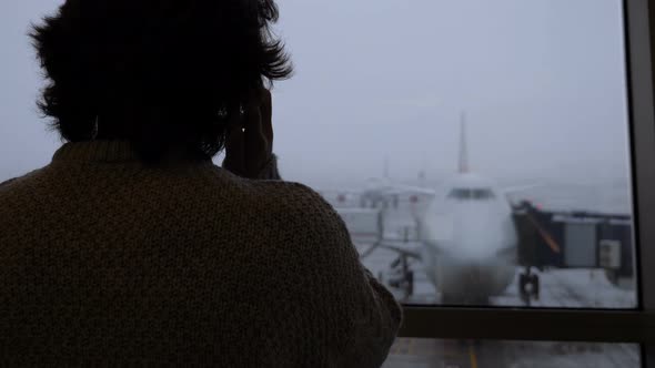 Silhouette of Male Passenger Talking on Phone at Airport alt