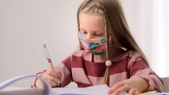 Little girl child with face protect mask studying at school in class and doing homework lesson alt