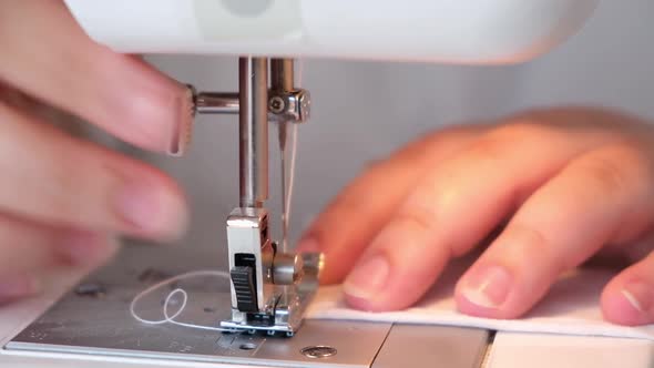 A Woman is Sewing the Hem of Curtains the Edge of a Pillowcase Clothes Sheets on Sewing Machine