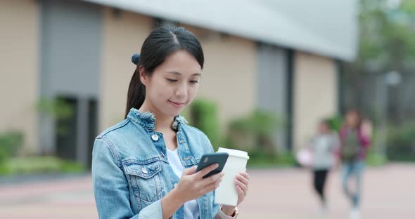 Woman use of mobile phone and holding coffee cup alt