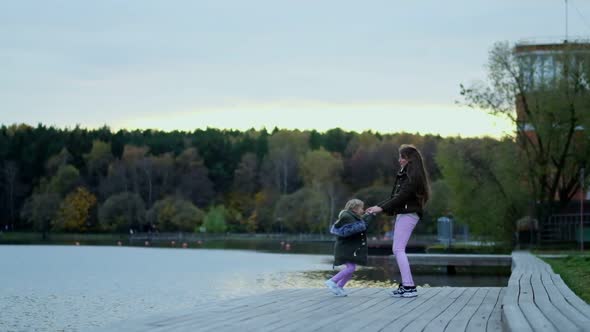 Happy Mom Walks with Her Daughter in the Autumn Park alt