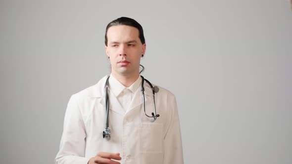 A Male Doctor in a Medical Gown Uses an Invisible Touch Screen