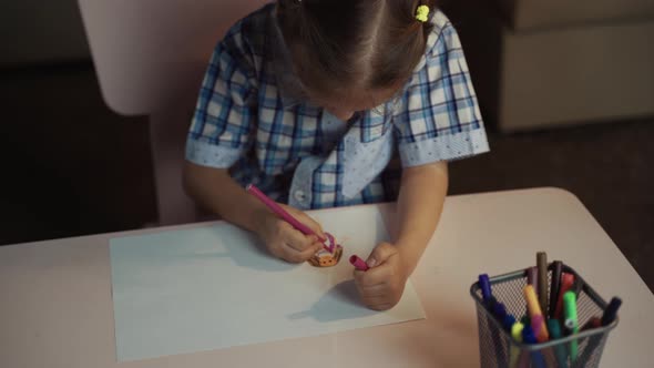 Girl Child Draws Colored Pencils On Paper Picture In Interior