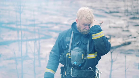 Firefighter is Standing in the Forest Fire Area and Looks Into the Camera alt
