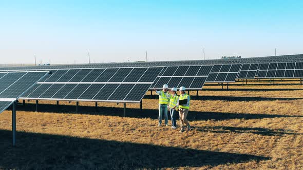 Three Solar Power Engineers Having a Discussion in at a Solar Power Station alt