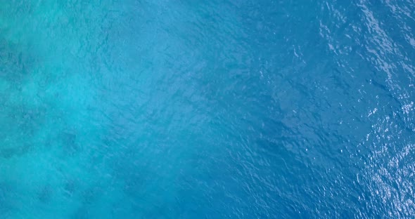 Wide overhead clean view of a sandy white paradise beach and blue sea background in colorful 4K alt