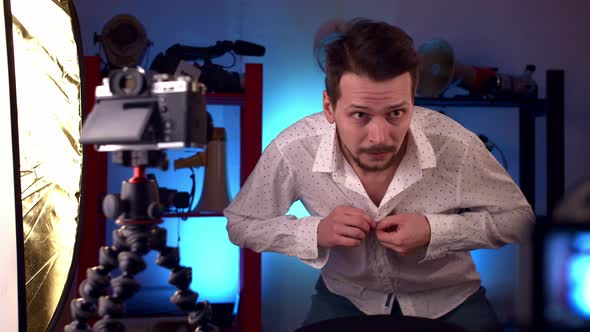 Man Prepares for Video Broadcast on Internet Buttons Shirt and Adjusts Hairstyle