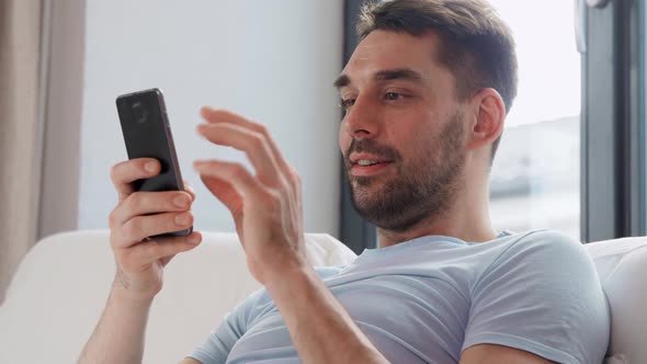 Happy Man with Smartphone in Bed at Home
