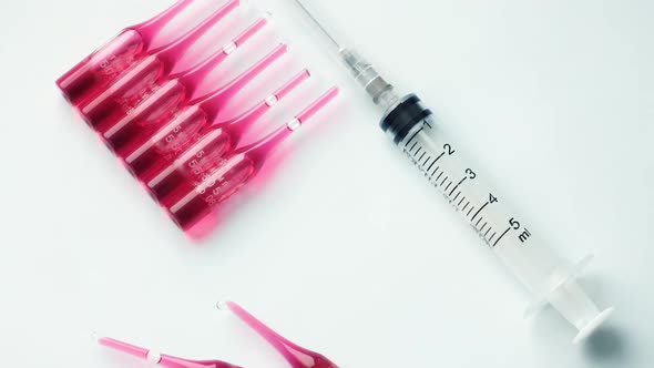 Syringe with Ampoules and Red Medicine Lie on a Pastel Blue Background alt