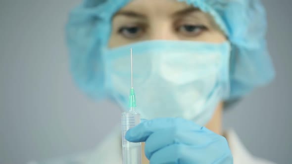 Experienced nurse preparing medical drugs for injection, health care system alt