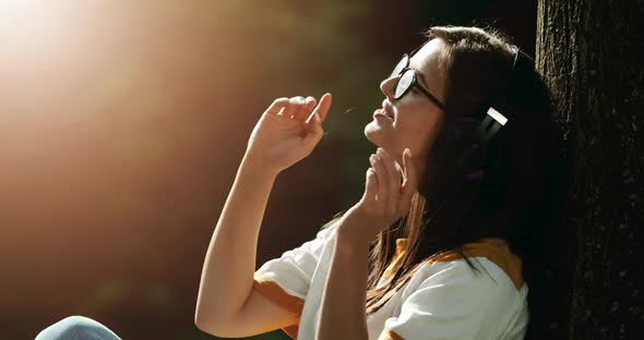 Woman in Headphones Listening To Music in Park