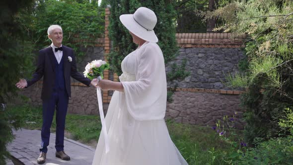 Cheerful Laughing Senior Bride Looking Back at Happy Groom Turning Looking at Camera Smiling alt