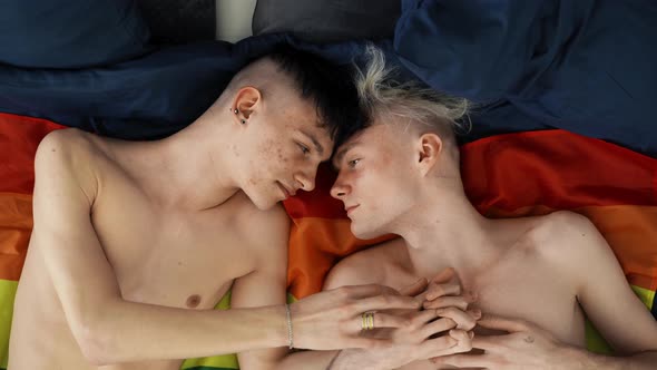 Two Gay Men Lovers Laying Side By Side on Flag LGBT Concept Slow Motion alt