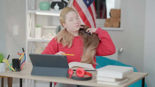 Portrait of Asian Teenage Girl Sitting at Desk Taking Off Wig and Tossing Hair alt