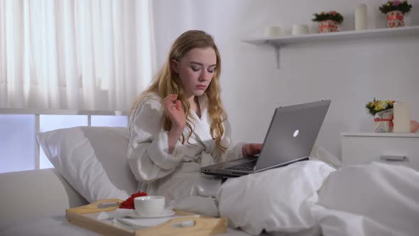 Girl in Robe Drinking Coffee in Bed and Working on Laptop, Freelance Concept alt
