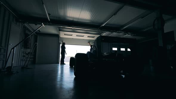 Two Men are Opening a Garage with a Racing Car in It alt