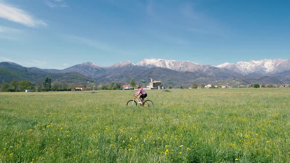 Slow motion: woman having fun by riding mountain bike on country dirt road on sunny day, scenic alpi