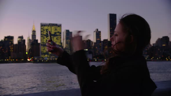 Woman in New York City taking photos of city with cell phone