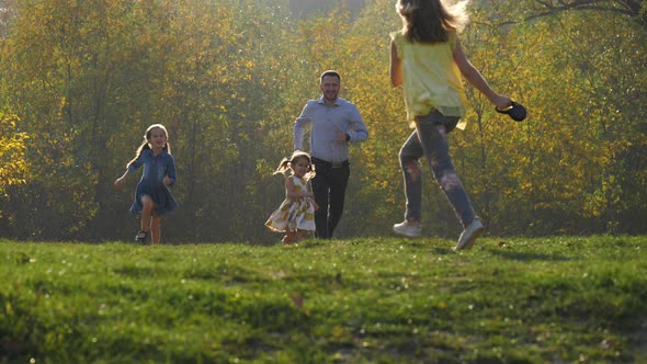 Father and daughters running in a park alt