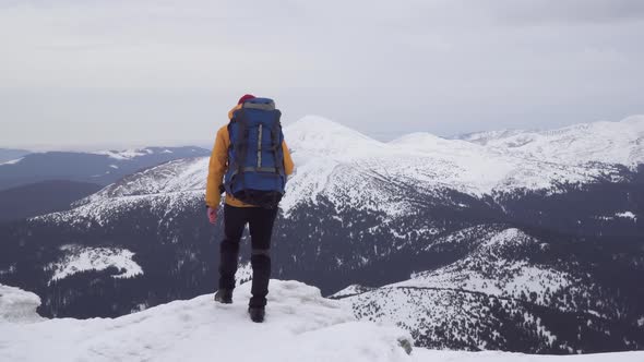 A Man with a Backpack Travels in the Mountains in Winter alt