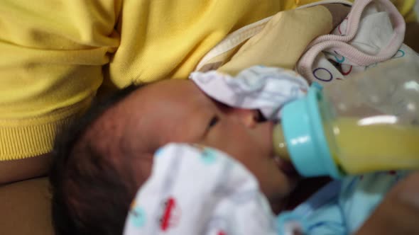 The newborn is eating breast milk from a bottle, slow-motion shot alt