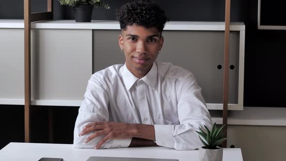 Millennial Afro American Man Sitting at the Table Looking at Camera and Smilling alt